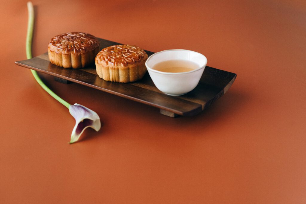 pexels-photo-9863615-9863615 Traditional mooncakes and tea on a wooden tray, perfect for celebrating the Mid-Autumn Festival.